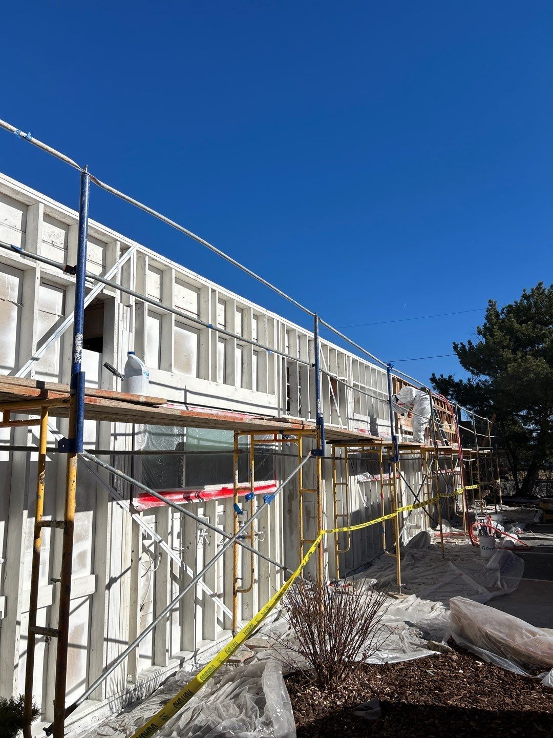 Scaffolding and construction on a white building against a clear blue sky.