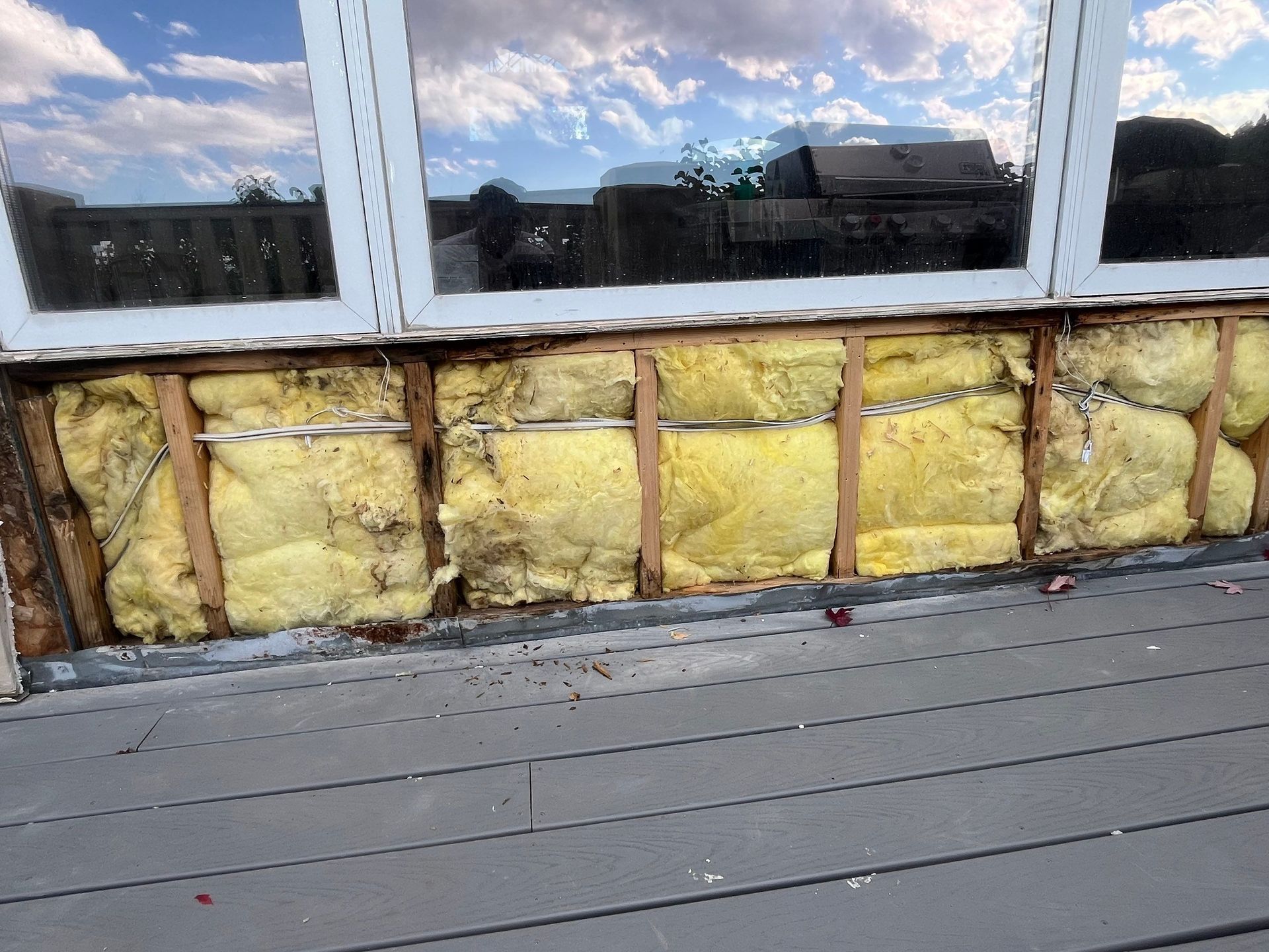 Exterior wall with exposed insulation and window, likely damaged by water. 