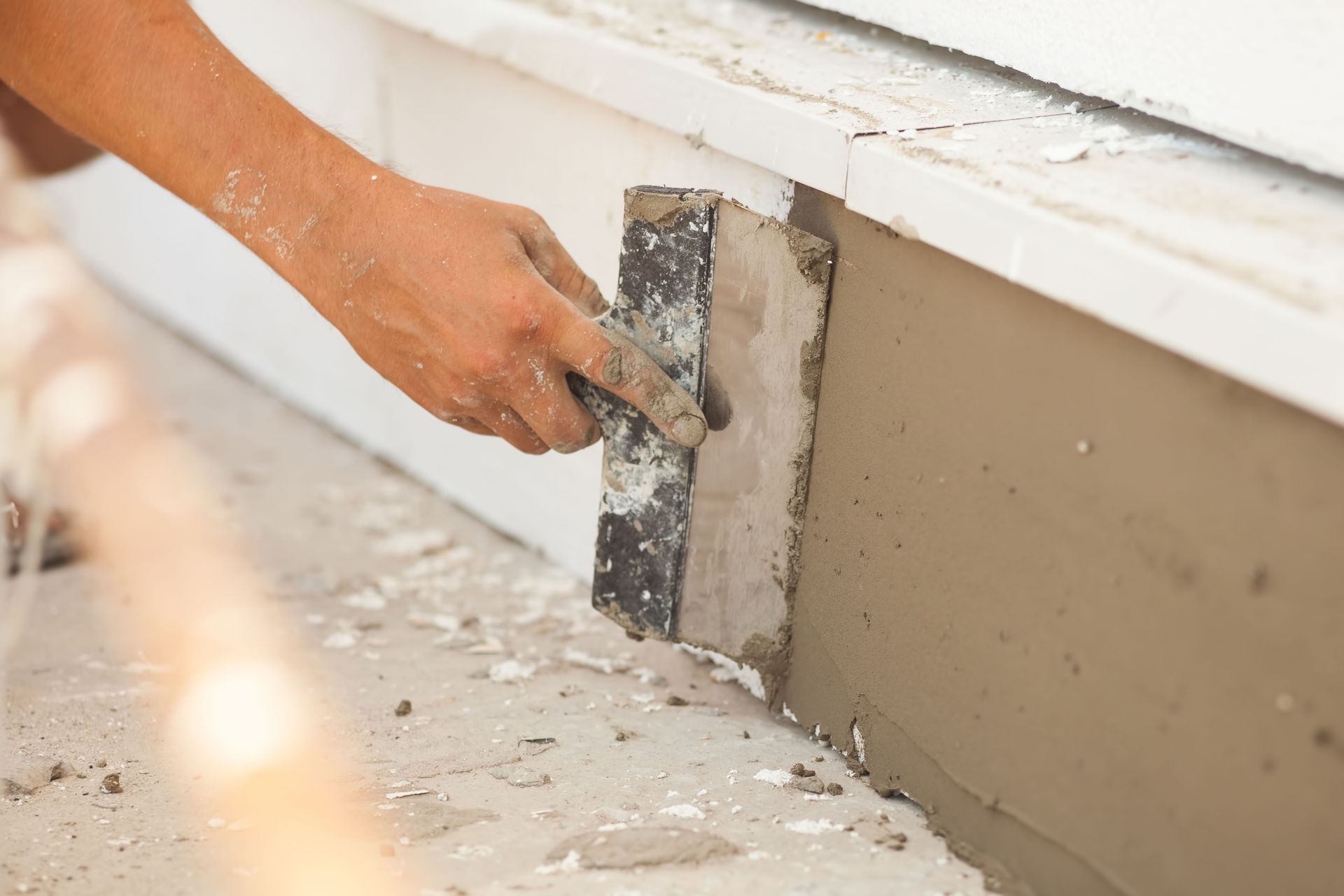 Person uses a trowel to apply stucco to a building's exterior.