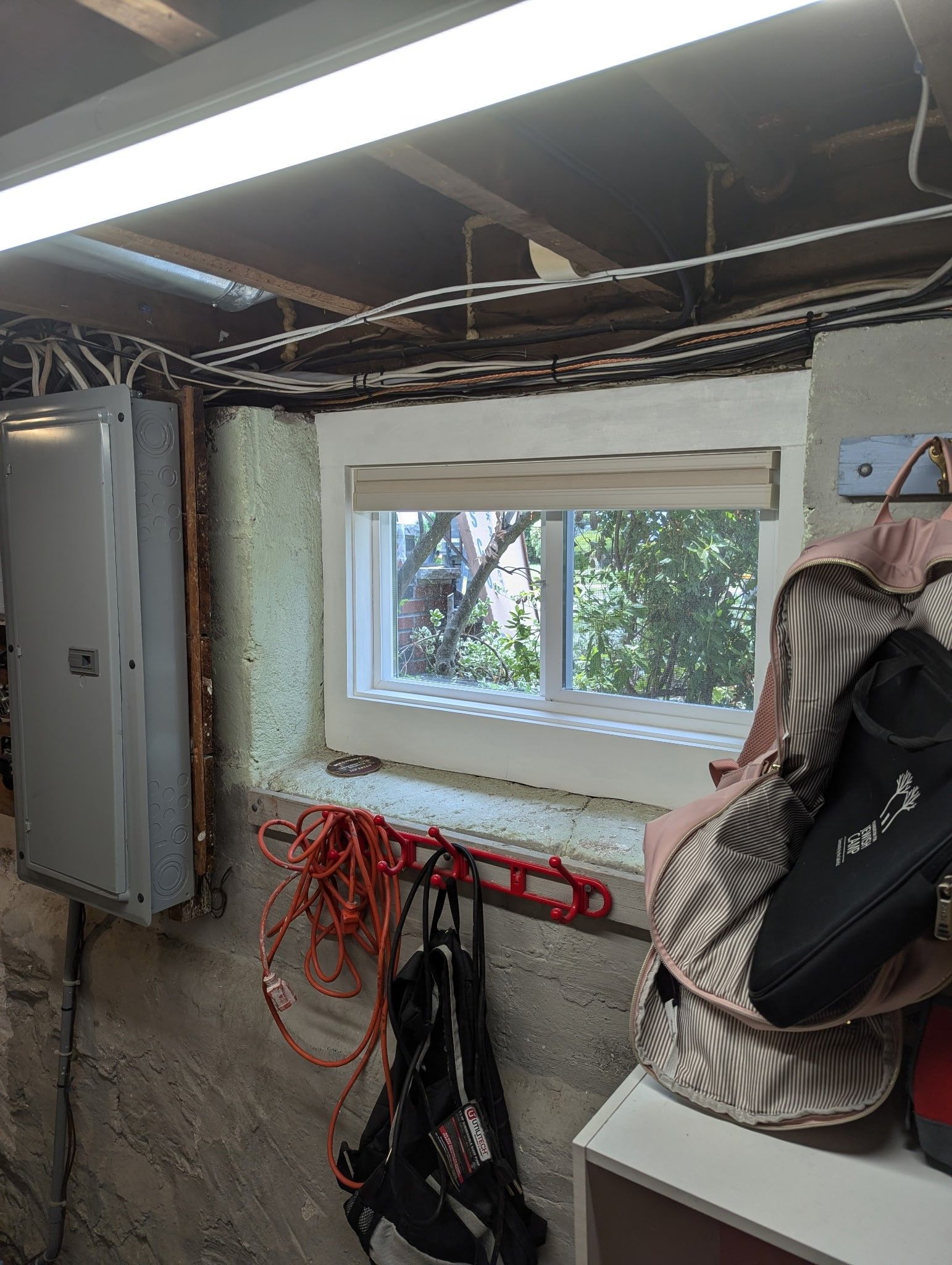 A room with a window and a backpack on a shelf.