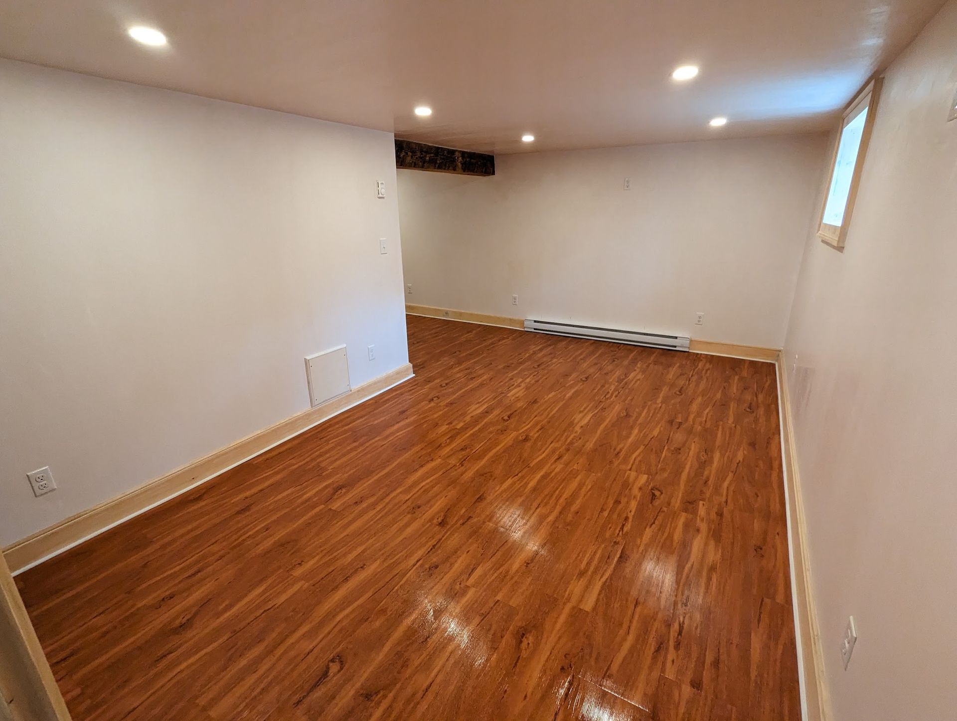 An empty room with hardwood floors and white walls.