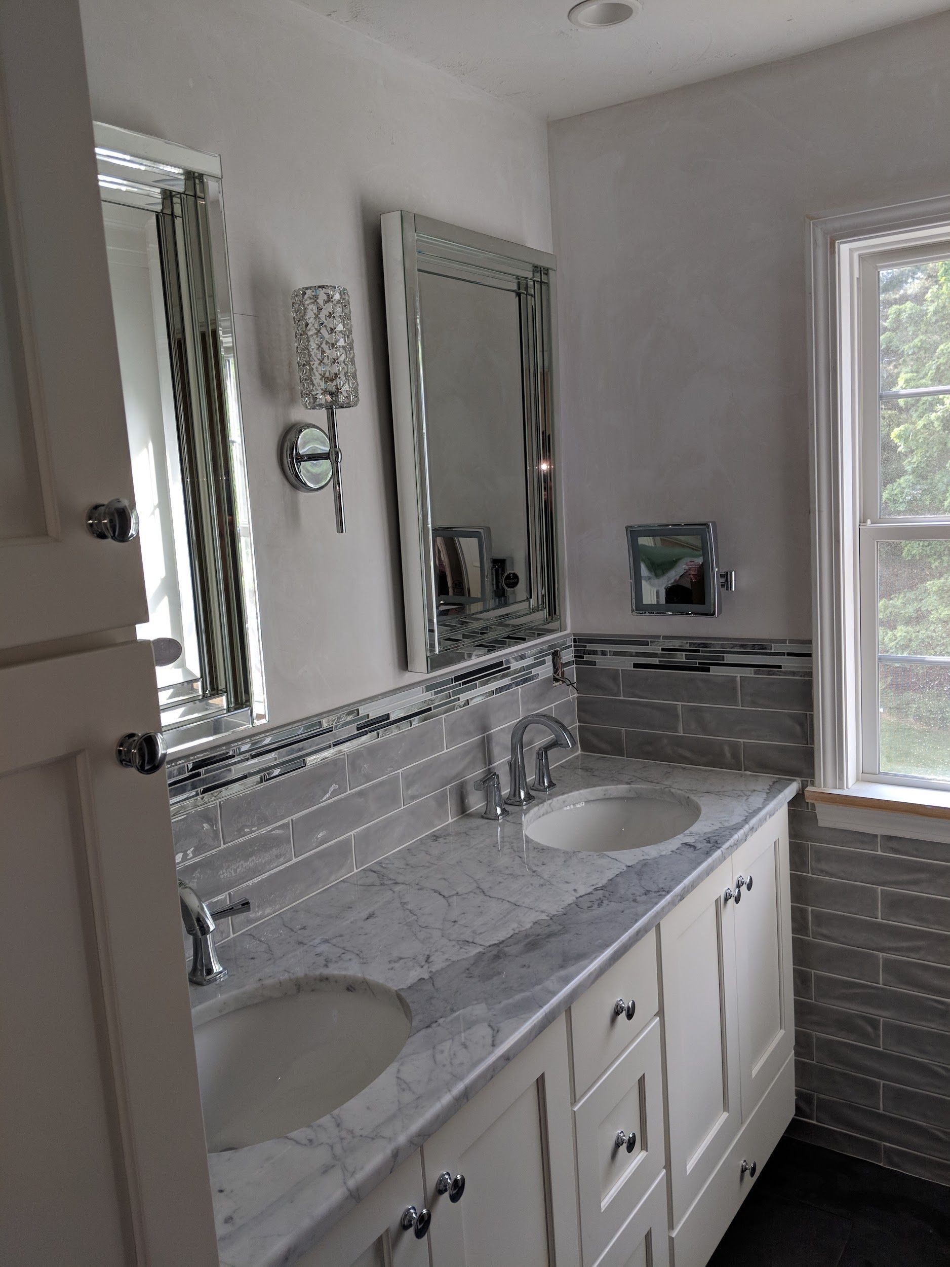 A bathroom with two sinks, a mirror and a window.