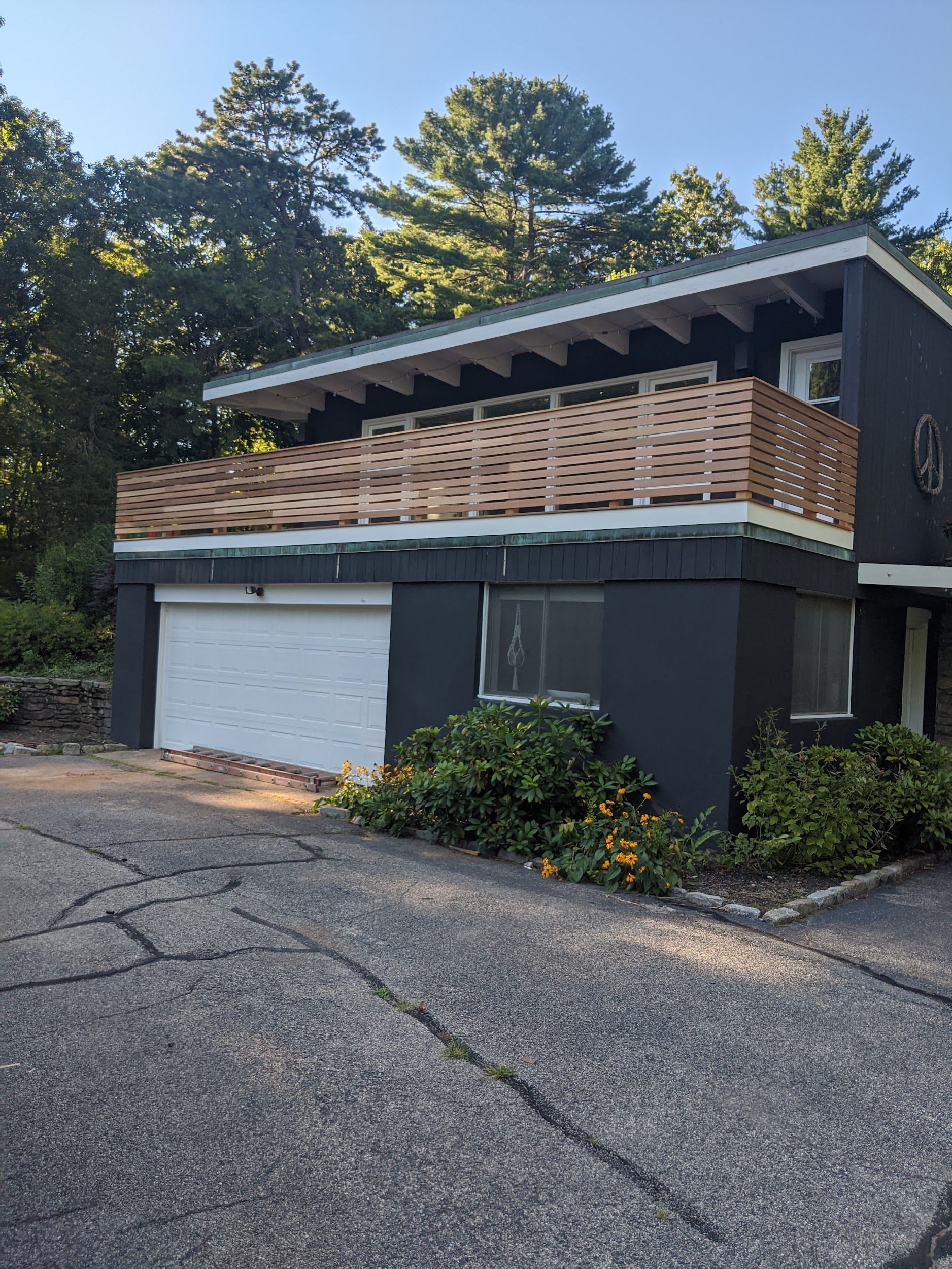 A black house with a white garage door and a balcony.