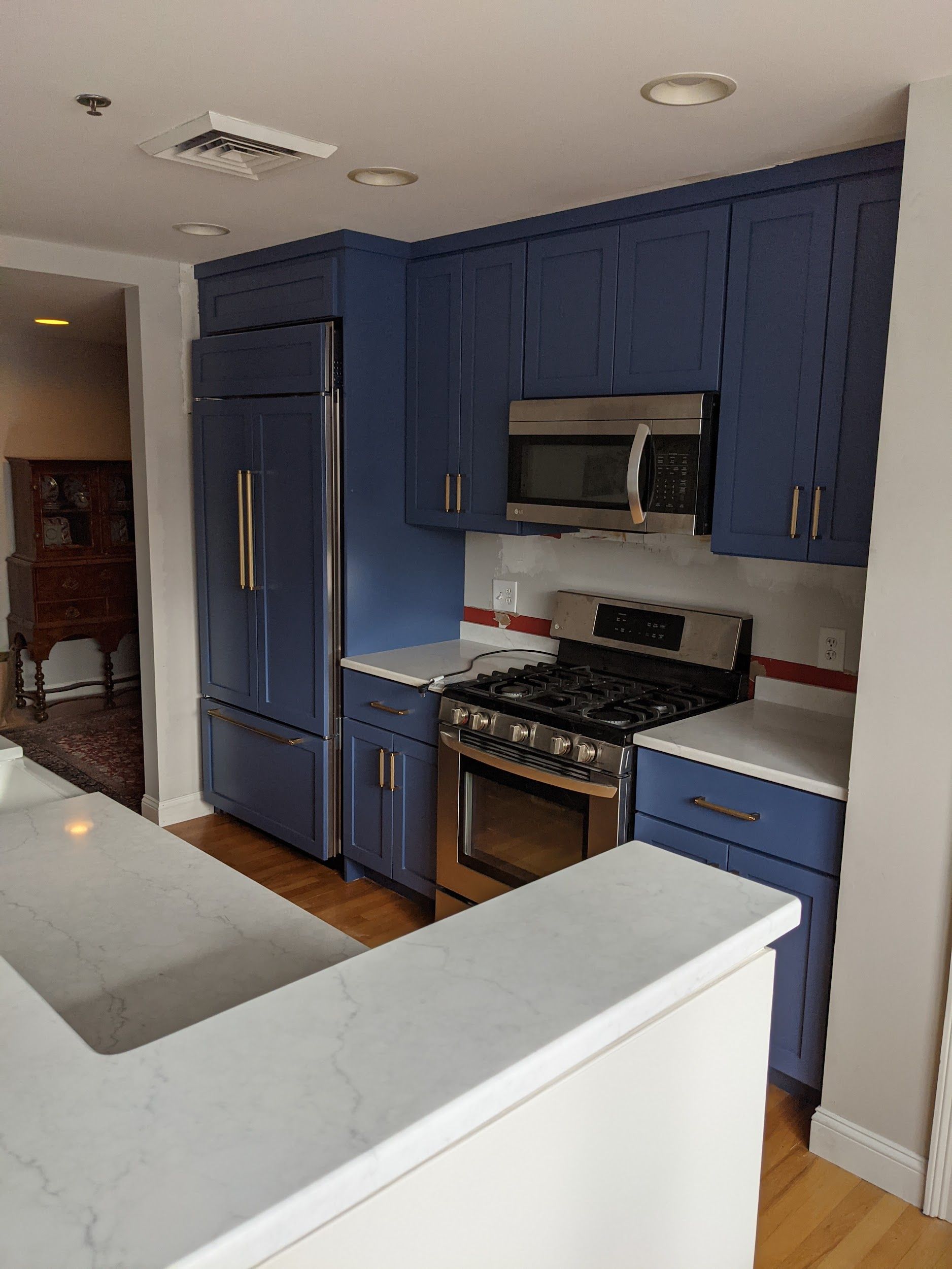 A kitchen with blue cabinets, a stove, a refrigerator, and a microwave.