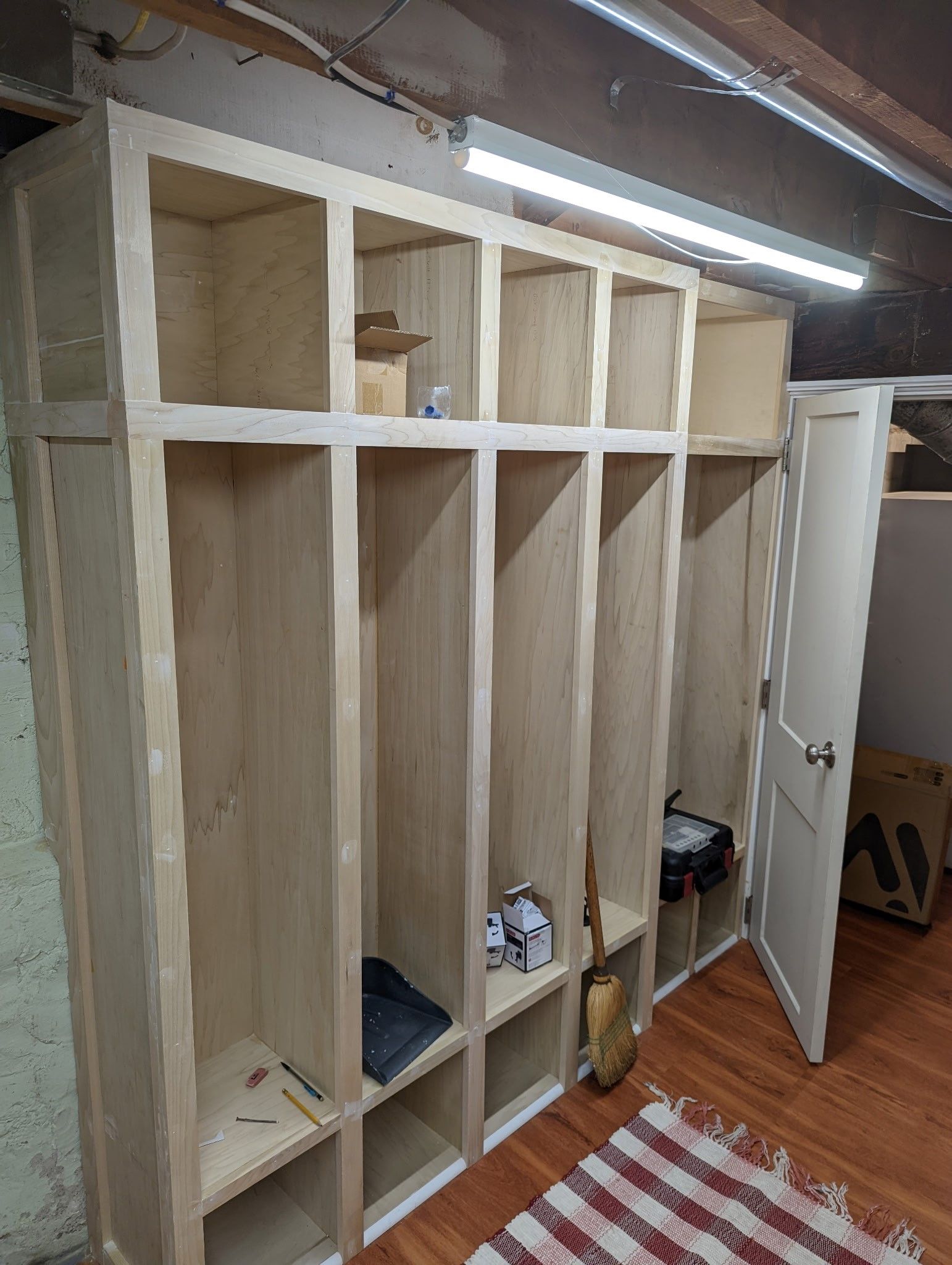 A wooden locker is being built in a basement.
