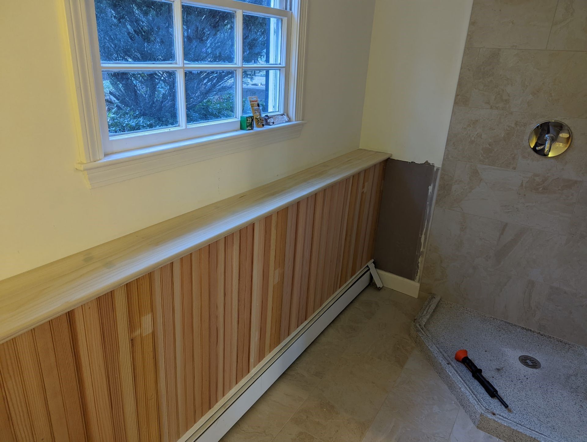 A bathroom with wood paneling and a window.