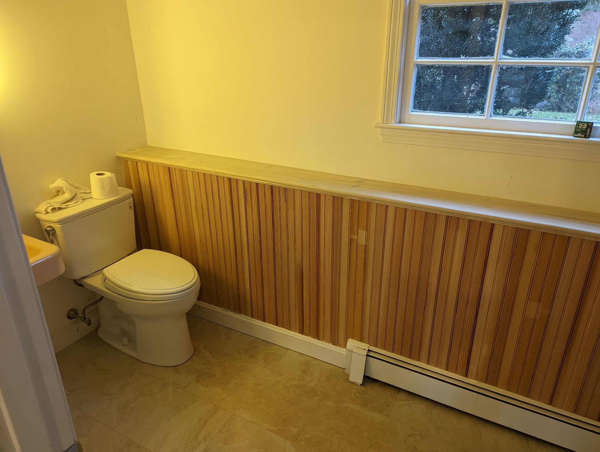 A bathroom with a toilet , sink and window.
