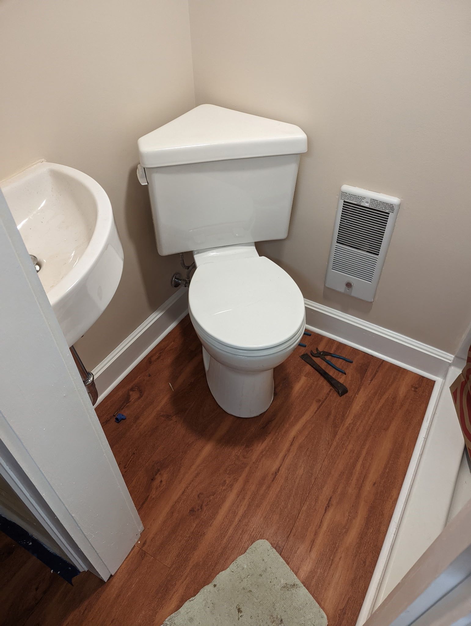 A toilet is sitting in a corner of a bathroom next to a sink.