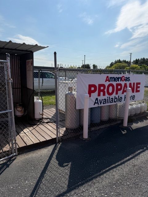 AmeriGas propane sign beside a small roadside kiosk and fenced lot on a sunny day.