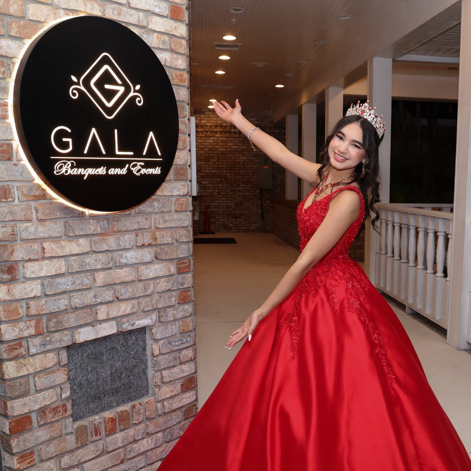 Woman in red gown and crown points toward a 