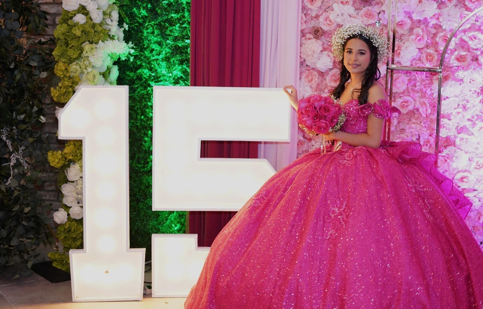 Woman in pink ball gown with bouquet poses near illuminated 