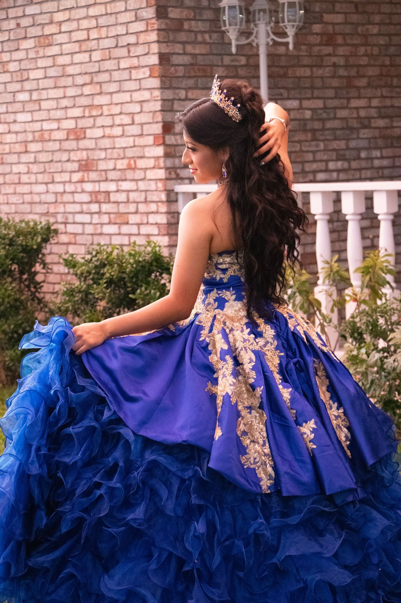 Woman in blue and gold formal dress poses outside.