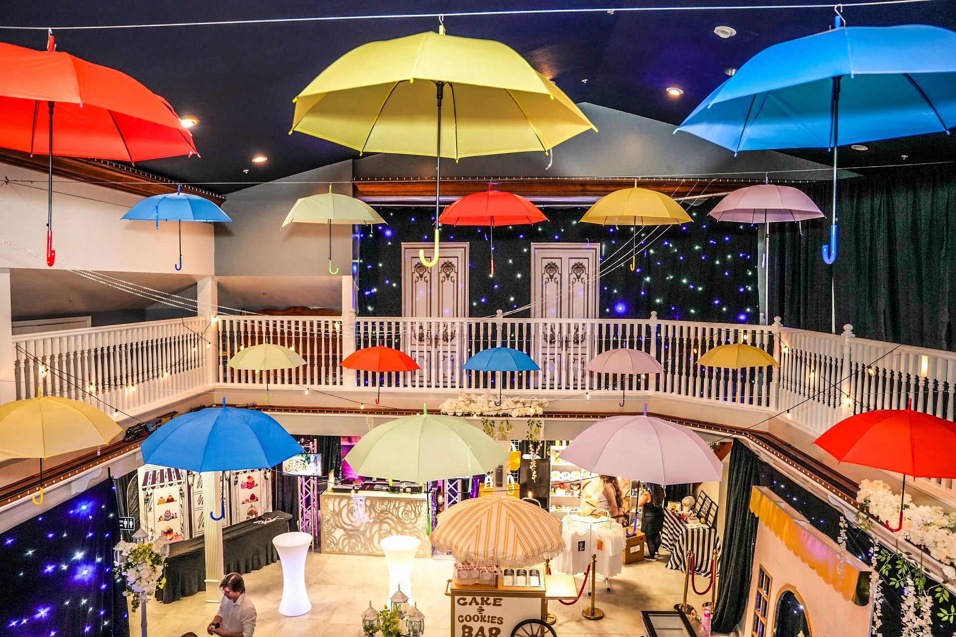 Colorful umbrellas suspended from a venue ceiling, decorated for an event.