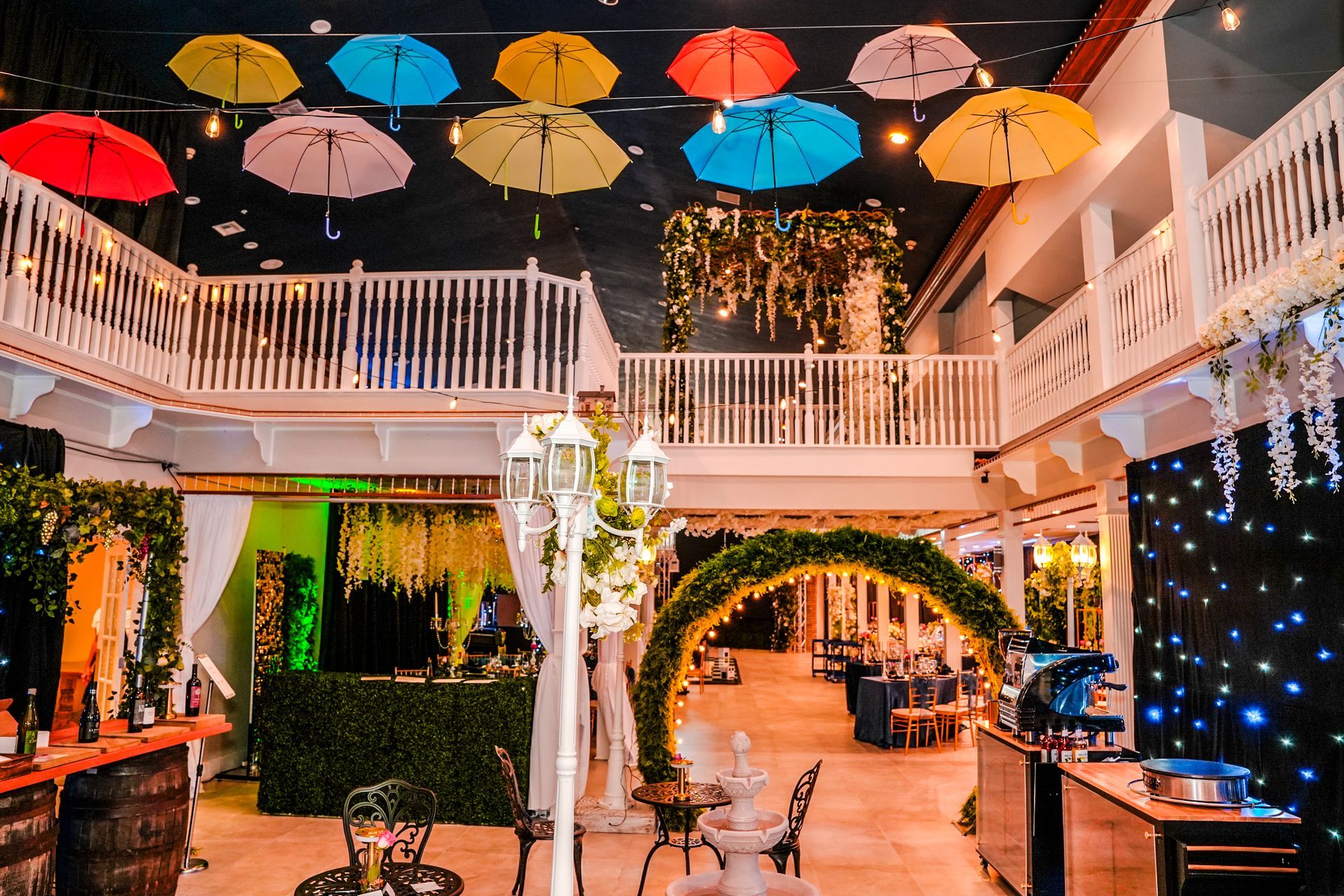 Brightly decorated event space with balconies, umbrellas, and archway; setting for a celebration.