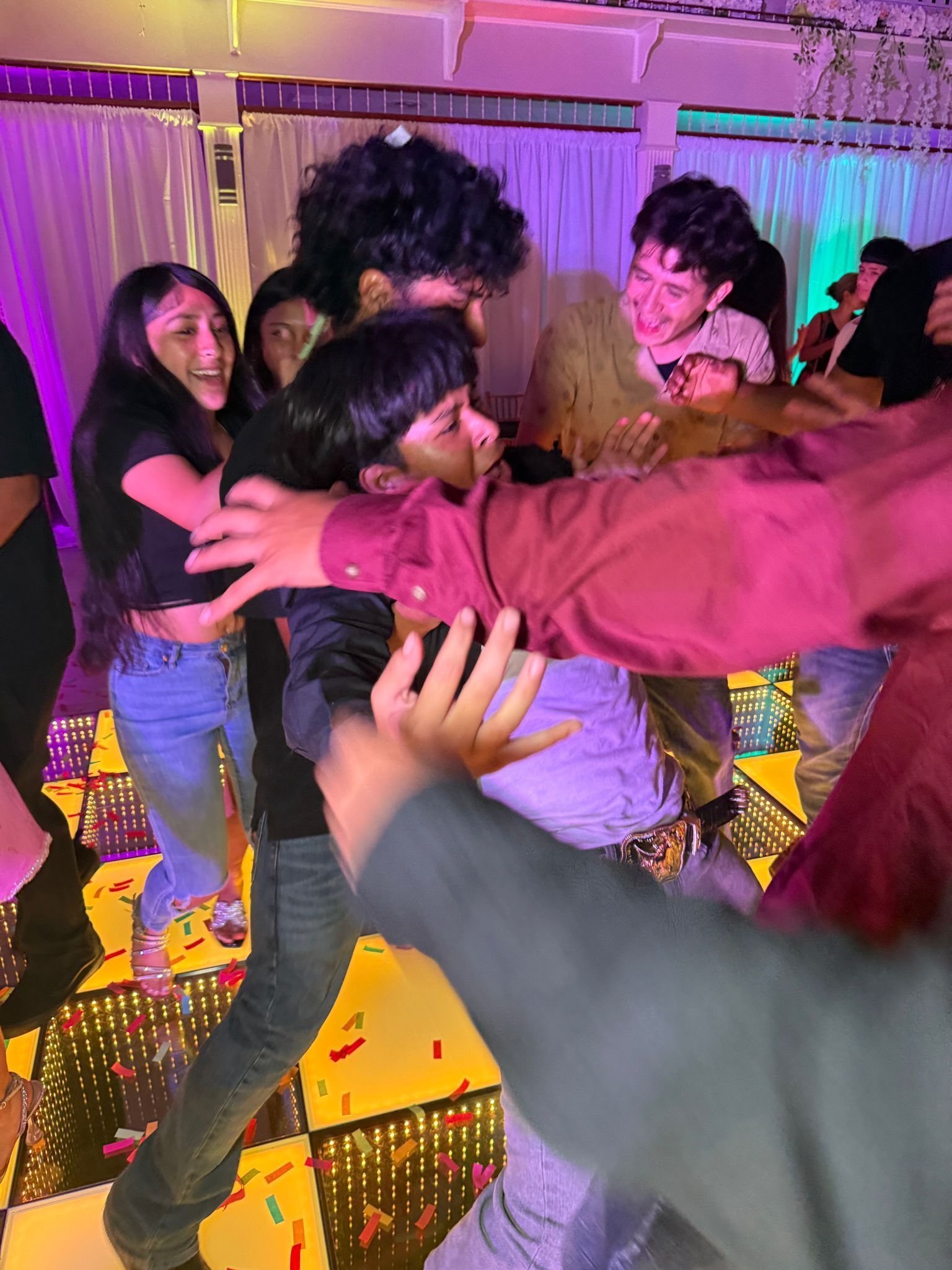 People dancing at a party; colorful confetti on checkered floor.