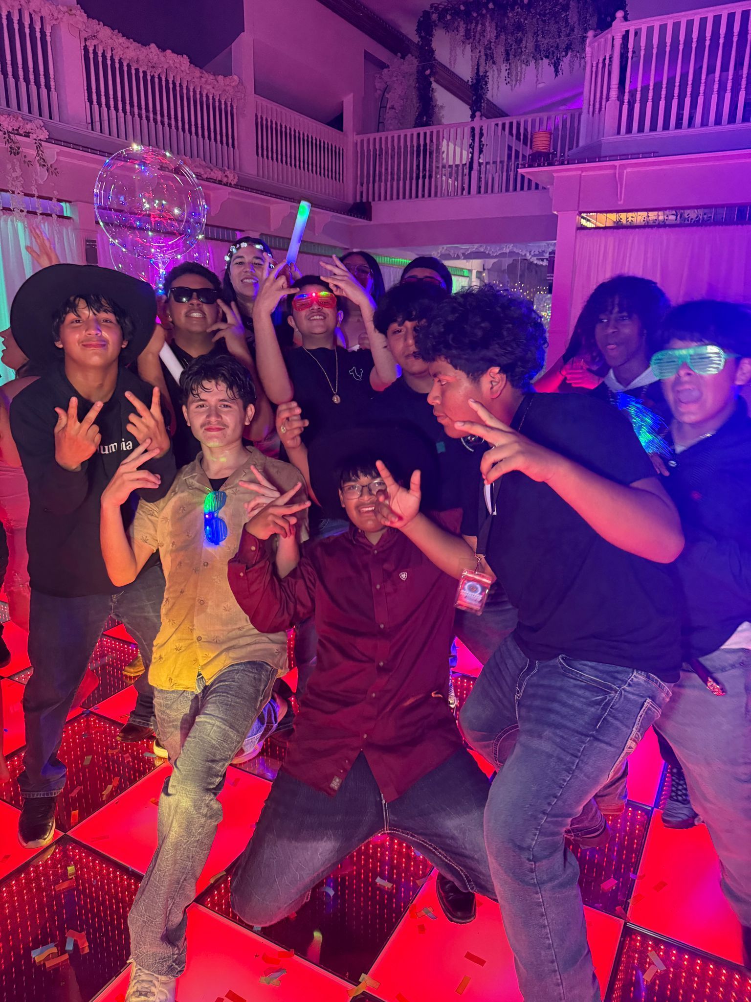 Group of people partying on a red dance floor with neon lights.
