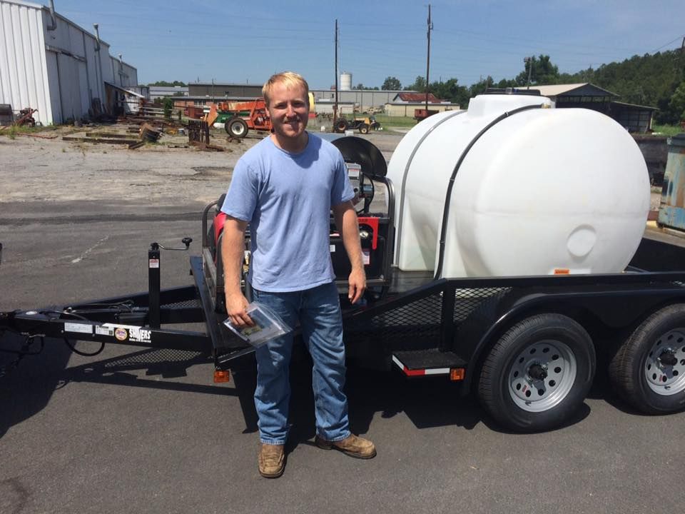 A man standing next to a trailer with a large white tank on it