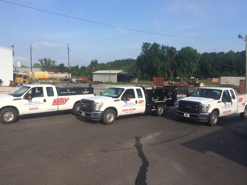 Three white trucks are parked next to each other in a parking lot.