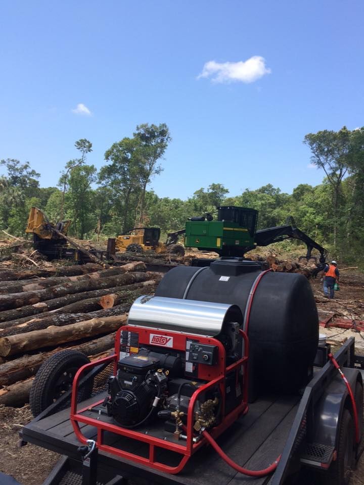 A john deere tractor is sitting on top of a trailer in a forest.