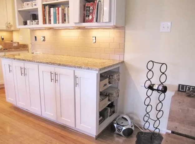 White kitchen cabinets with granite countertop and tan backsplash.