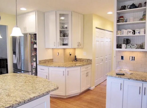 Kitchen with white cabinets, granite countertops, and island.