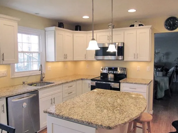 White kitchen with granite countertops, stainless steel appliances, and island.
