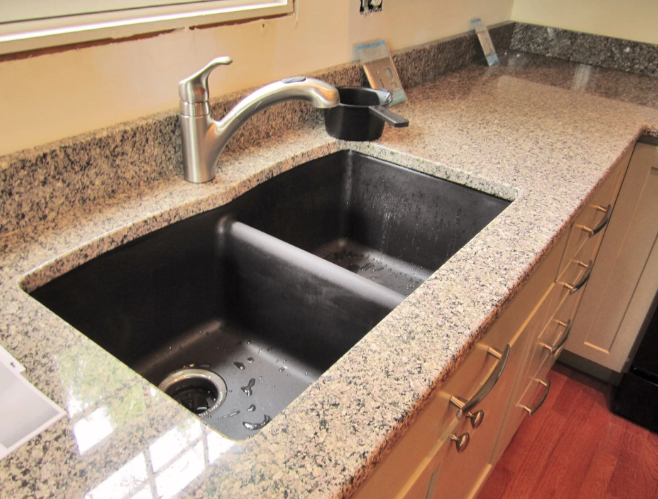 Kitchen sink with granite countertop and faucet.
