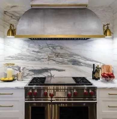 Kitchen with marble backsplash, stainless steel range hood, brass accents, and stove.