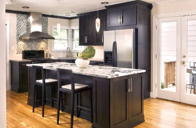 Dark kitchen with island, stainless steel appliances, and wood flooring.