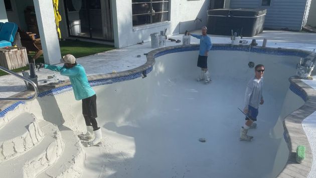 Children playing in a shallow empty pool in a backyard, with one child standing on the edge and another climbing out.