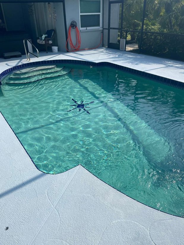 Backyard swimming pool with clear water and a concrete deck under bright sunlight.