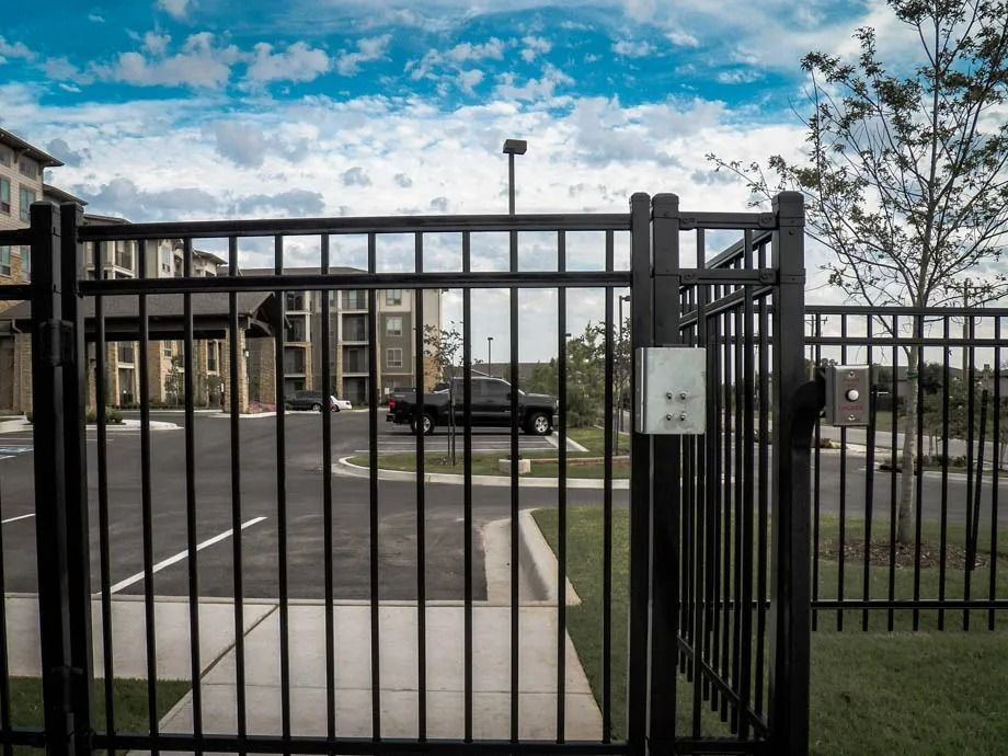 Black metal gate entrance to a parking lot under a blue sky