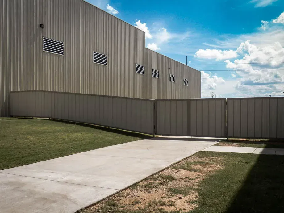 Concrete walkway beside beige industrial building under a blue sky