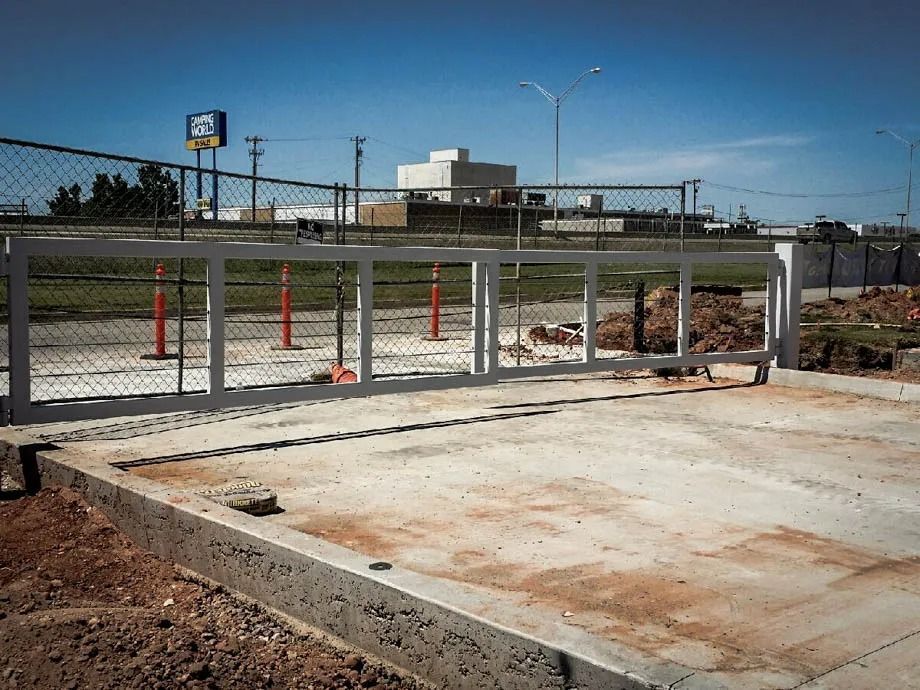 Empty concrete foundation with metal framing and chain-link fencing at a construction site