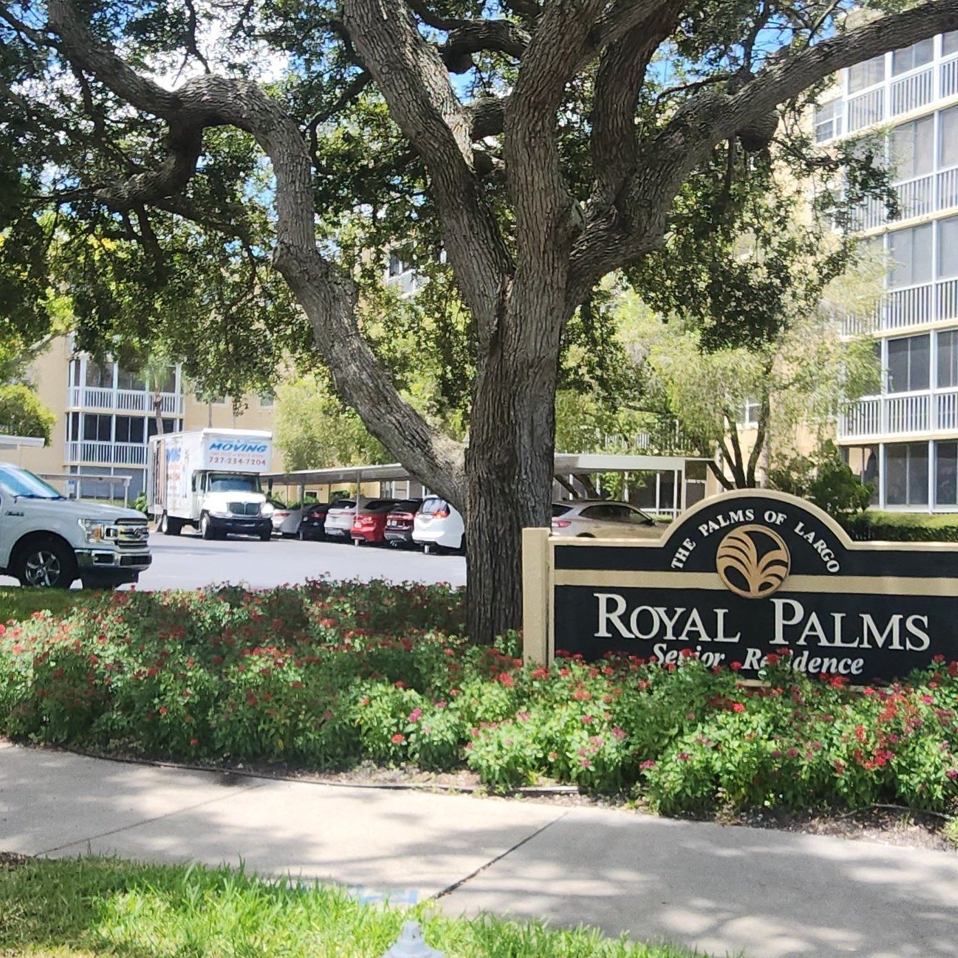 Royal Palms Senior Residence sign with building and parked cars.