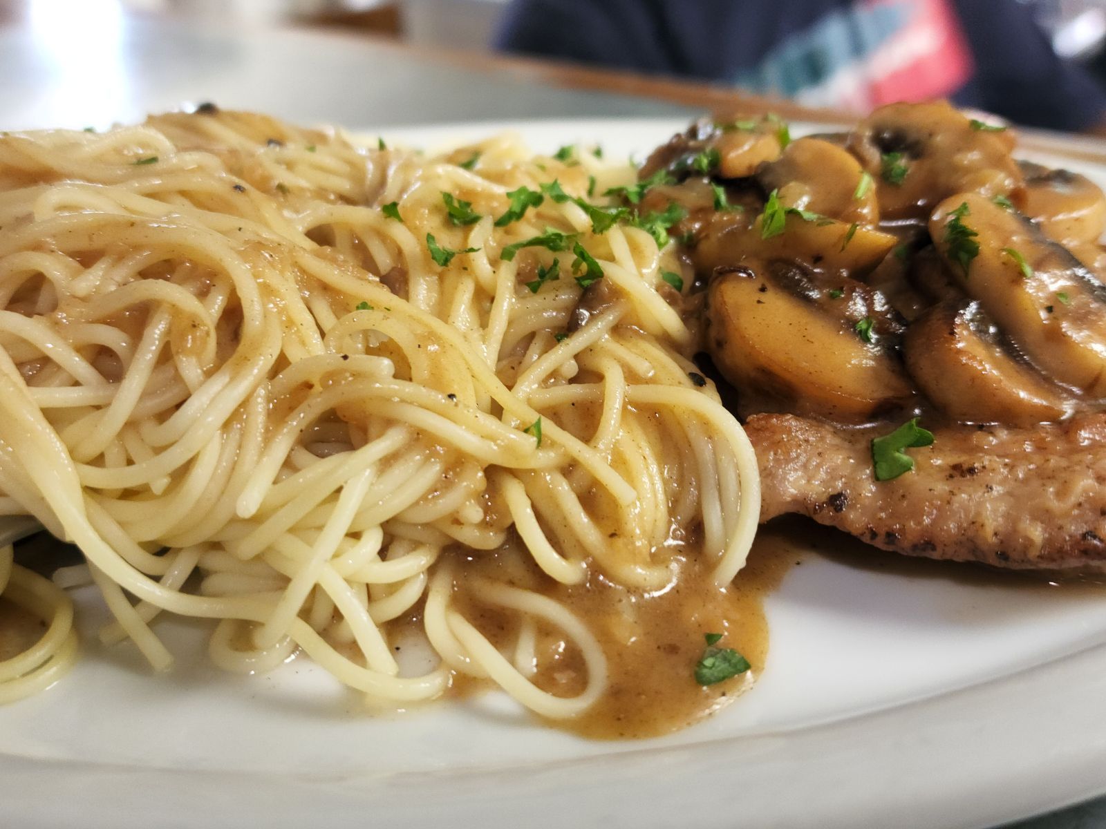 A white plate topped with spaghetti and meat with mushroom sauce