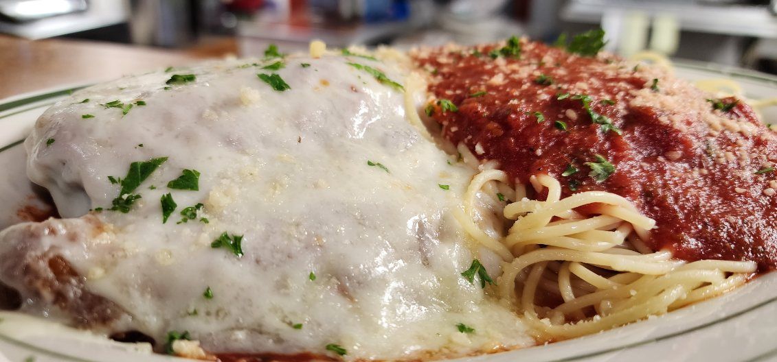 A plate of spaghetti and meatballs with sauce on a table.