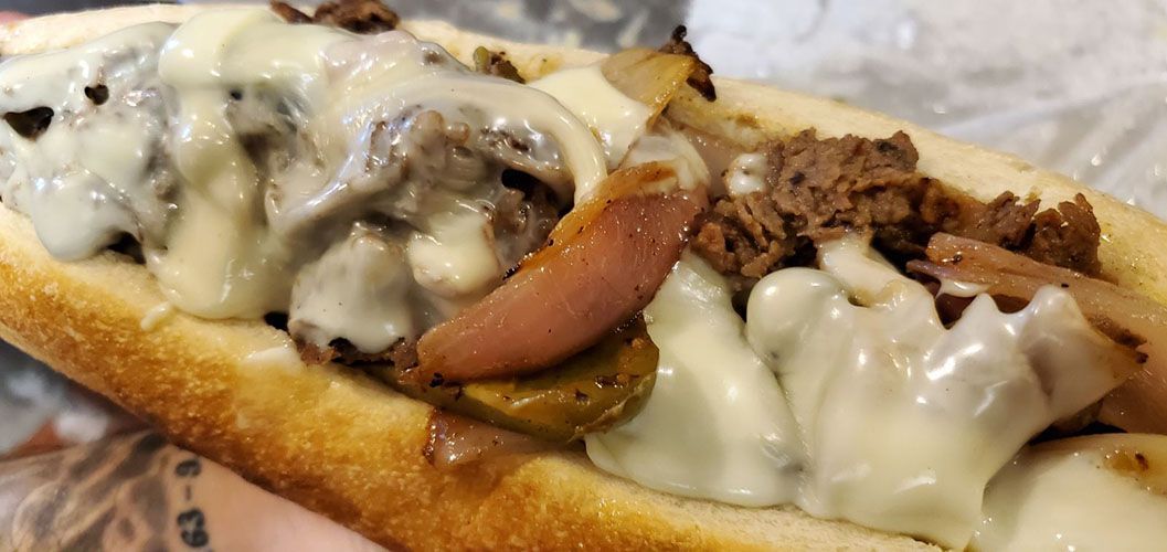 A close up of a steak and cheese sub sandwich on a bun.