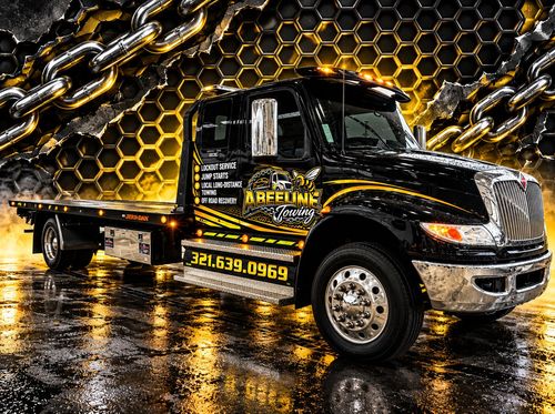 Black and gold tow truck on wet pavement with chain-link backdrop and company branding