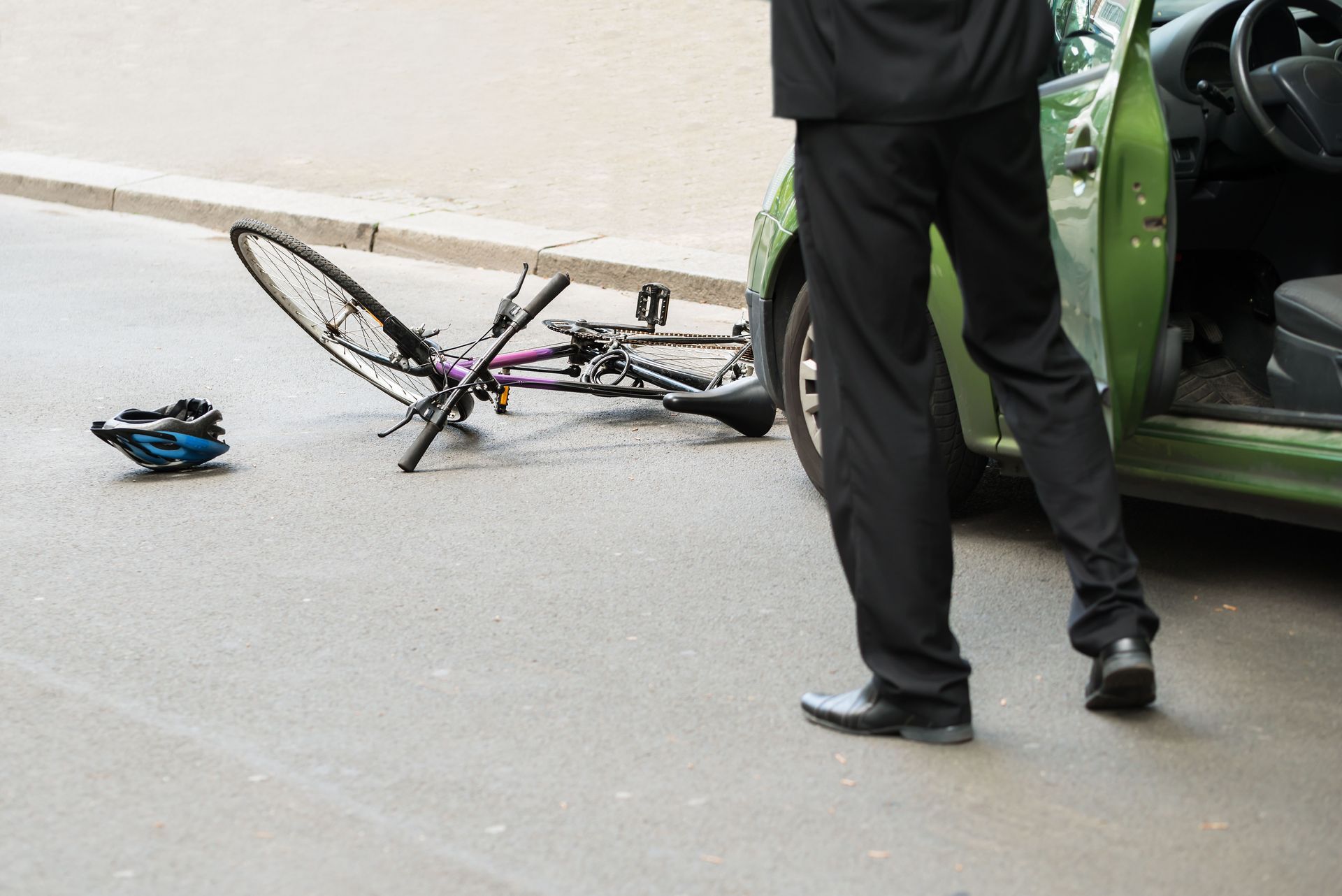 A woman is sitting on the ground next to a bicycle and a helmet.