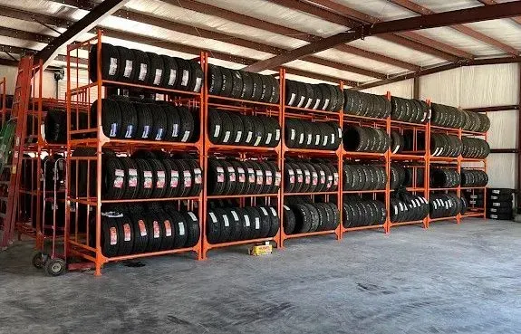 Stacked tires on red metal racks in a warehouse-like storage area.