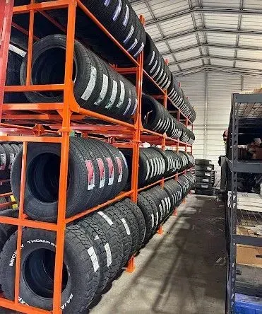 Rows of black tires stacked on orange racks in a warehouse aisle
