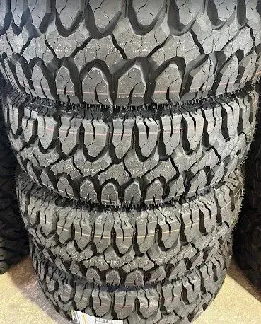Stack of black and gray tires with rugged tread patterns.
