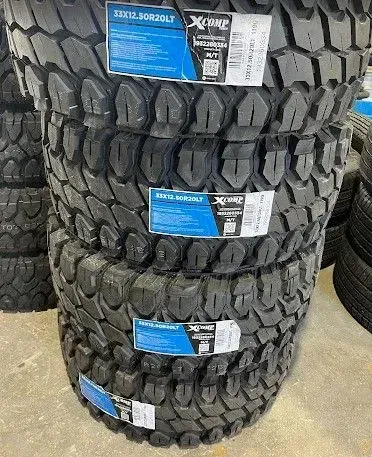 Stacked black off-road tires with blue-and-white labels in a store display.