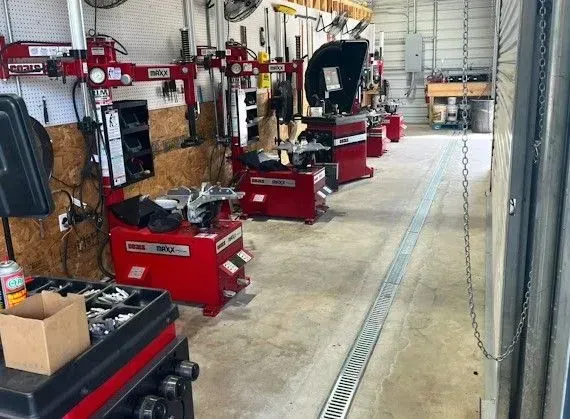 Auto repair shop with red tire-changing machines and tools lined along a concrete bay