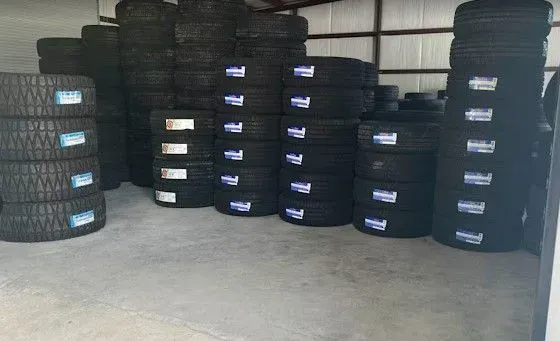 Stacks of black tires stored in a warehouse on a concrete floor.