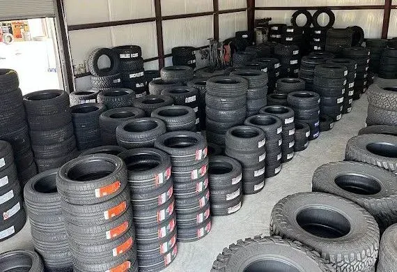 Stacks of black tires arranged in rows inside a warehouse or tire shop.
