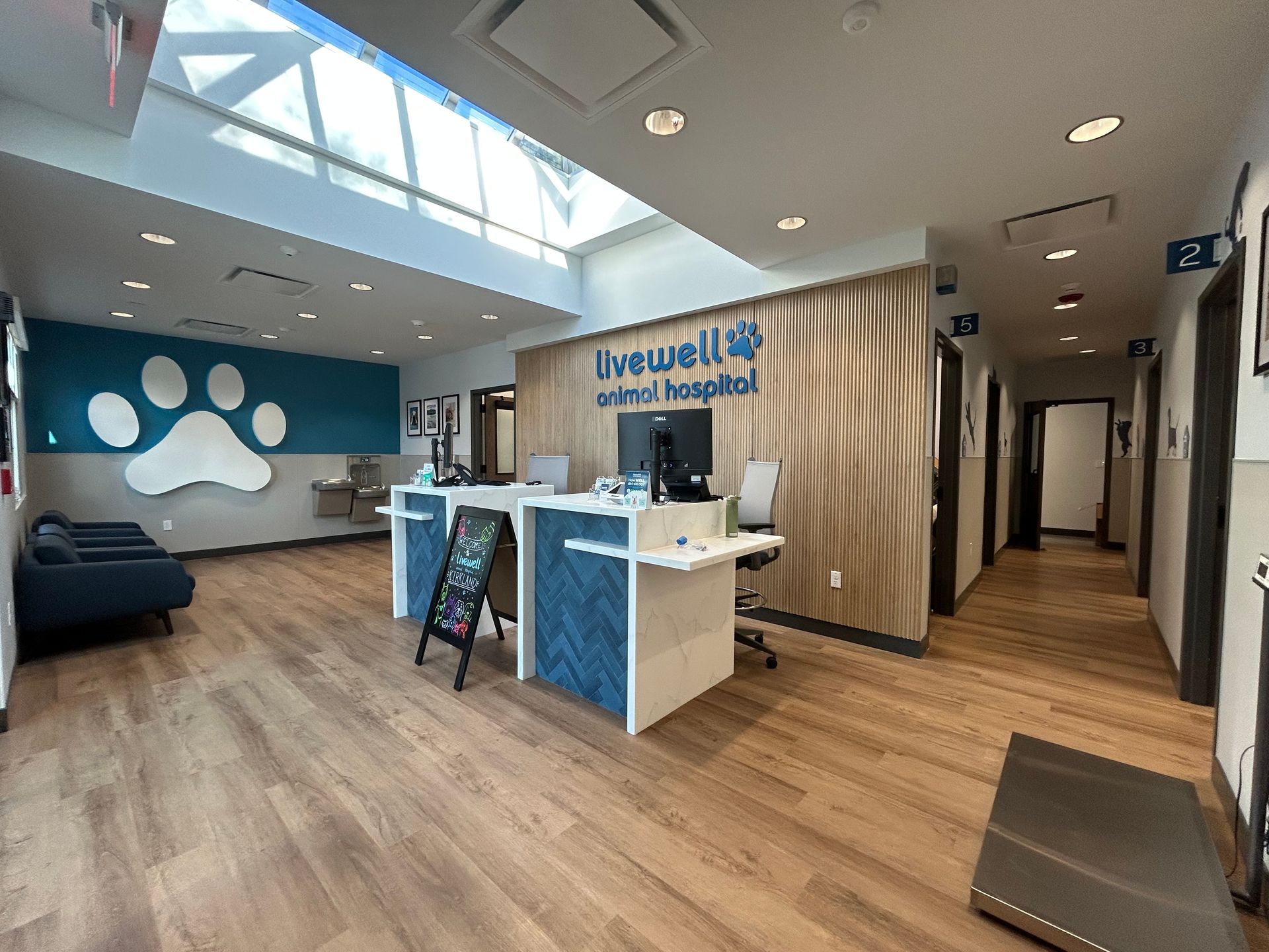 Reception area of a veterinary clinic with a paw print, waiting area, and several examination rooms.