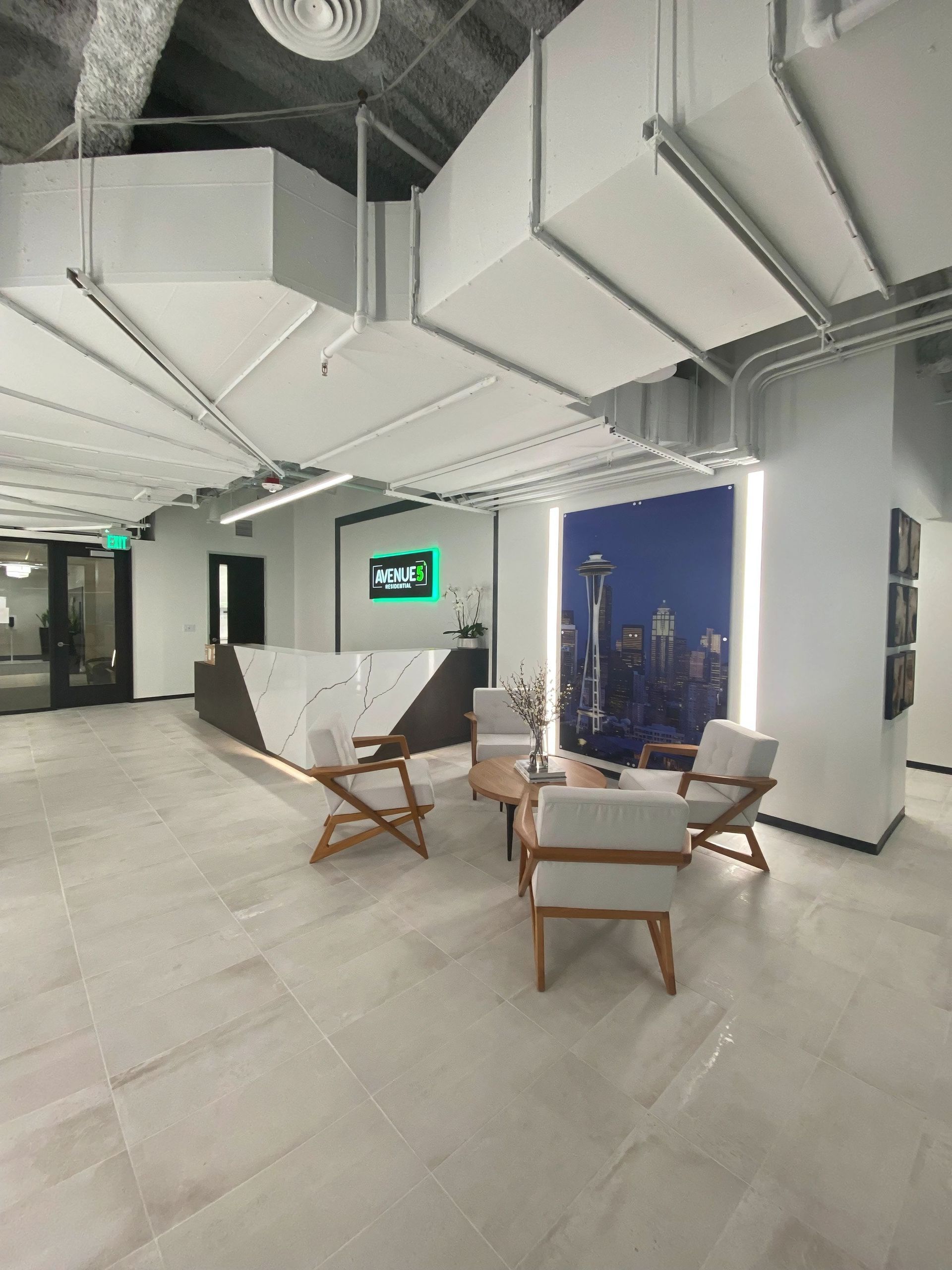 Modern office lobby with a reception desk, seating area, and cityscape mural.