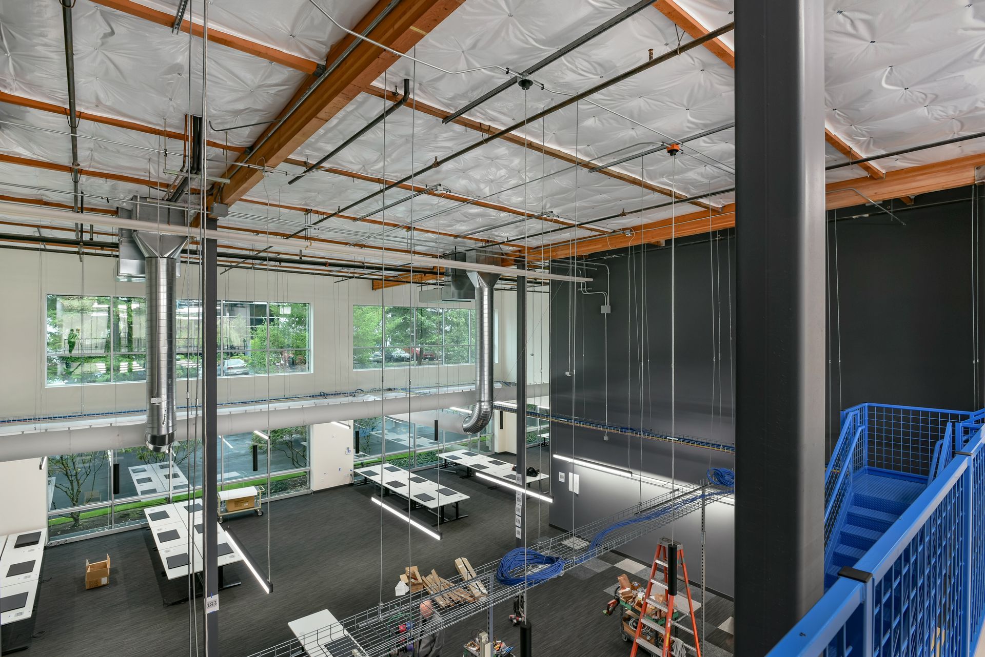 Modern office interior with desks, windows, and exposed beams. Overhead view.
